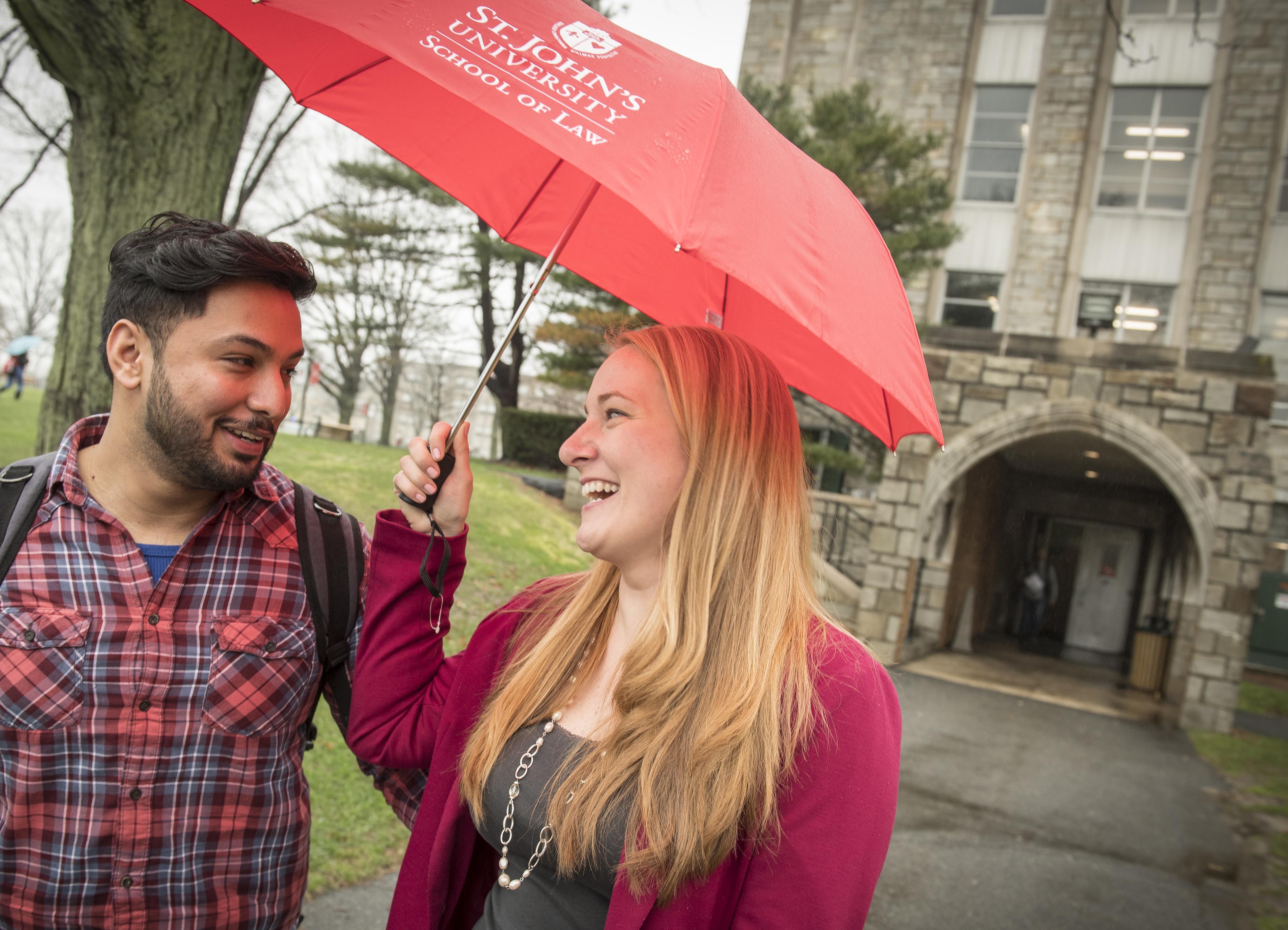 Two students walking in the rain with umbrella